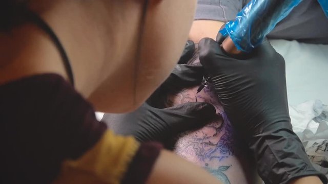 tattoo artist tattooing a tattoo of a lion, detail on the tattoo machine needle, slow motion