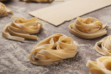 Raw tagliatelle nest and dough on kitchen table