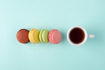 A cup of coffee with colorful macarons.