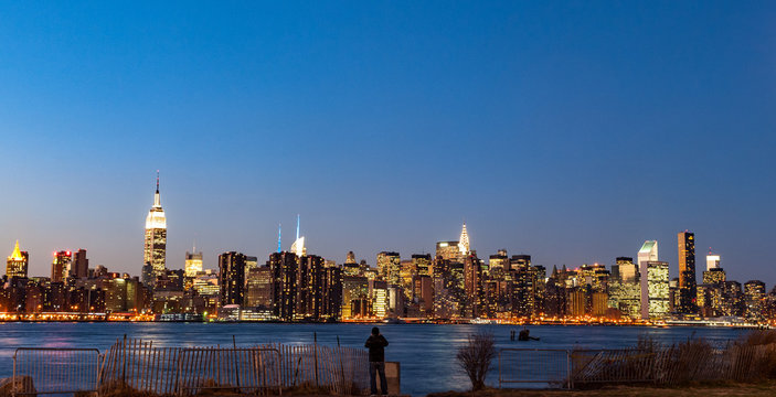 View of Manhattan skyline lit up at dusk in the distance from Williamsburg, Brooklyn