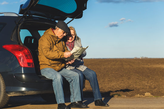 Happy senior couple on a road trip, they are using map for direction.