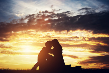 Silhouettes of a couple in love sitting and hugging