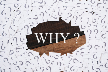 white paper note with question mark and WHY word in the center on wooden table. WHY concept...