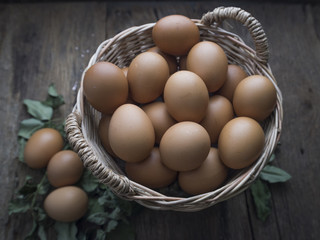 Fresh eggs in basket on old wooden background