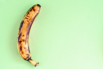 One very ripe yellow nutritious bananas on a green background