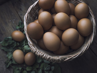 Fresh eggs in basket on old wooden background