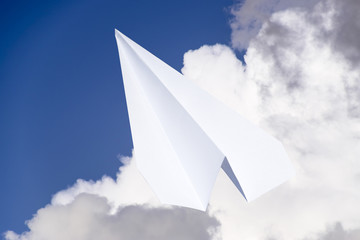 White paper airplane in a blue sky with clouds. The message symbol in the messenger
