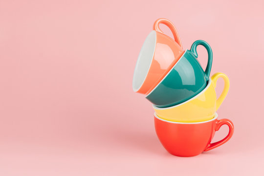 Colorful stack of cups for latte coffee in a vintage pastel colored tone on pink background with copy space.
