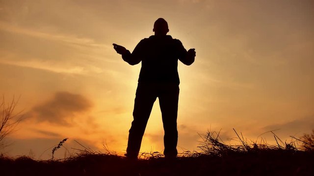 man warrior monk practicing silhouette karate kung Fu on the grassy horizon at sunset. Karate kick leg. Art of self-defense. Silhouette on a background of dramatic clouds at lifestyle sunset nature