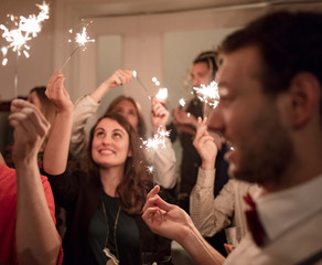 Group of friends using sparklers at party