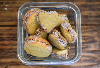 Kekse und Plätzchen in Herzform mit Füllung in Glasschüssel auf braunem Holztisch © Alexandra