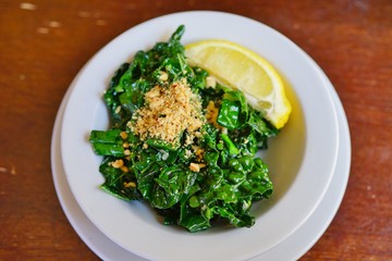 Bowl of sauteed green kale with lemon and hazelnuts