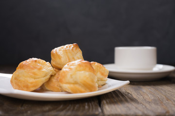 Delicious eclairs sprinkled with icing sugar, stand on a wooden table. Copy spase.
