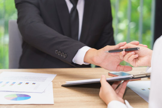 Businessman says no or hold on when woman giving pen for signing a contract.