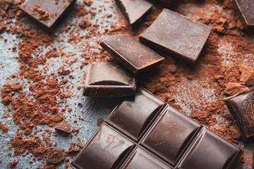 Crushed chocolate bar pieces and cocoa on gray background