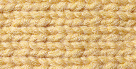 Knitting from woolen threads of orange color. The texture of the canvas is handmade.
