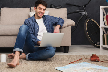 Man with laptop planning vacation, booking tickets