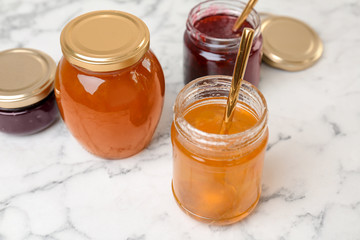 Jars with different sweet jam on table