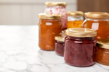 Jars with different sweet jam on table