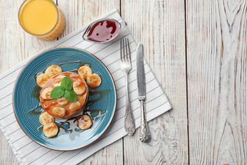 Plate with delicious pancakes on wooden table