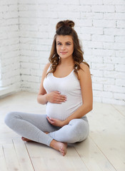 A young pregnant woman is engaged in fitness on the floor. The concept of pregnancy health.