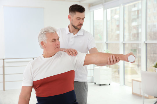 Young physiotherapist working with senior patient in clinic