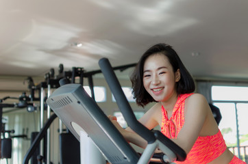 asian young beautiful smile woman slim body exercising cardio training on bicycle in fitness gym for good healthy at the morning, bodybuilder, lifestyle, exercise fitness, workout and sport concept