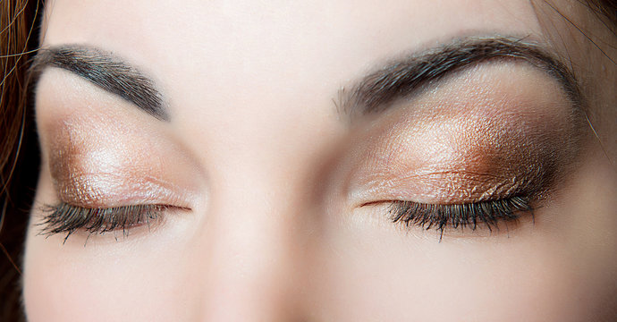 Professional make-up on closed eyes of a close-up girl on a black background. Female make-up.