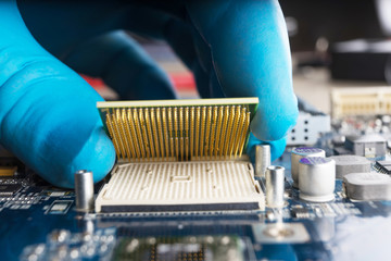 A gloved hand, placing a CPU on the motherboard. Macrophotographies.