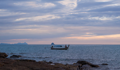 Colorful seascape with lonely traditional thai boat with fisherman at evening fishing, scenic...