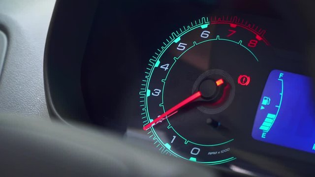 Closeup of car dashboard with focus on tachometer, with idling the gas and loading engine to maximum power