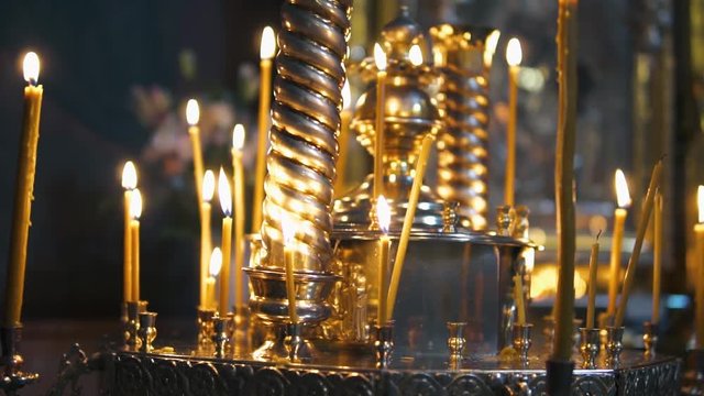 atmosphere of the Christian church, many candles burn, slow-motion shooting, smooth movement, camera slide, icons and religion, concept sacred rituals, wedding, baptism, communion, prayers to God