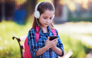 Schoolgirl using smartphone outdoors. Education, lifestyle, technology concept