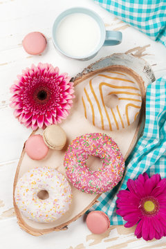 Milk, donuts and flowers on wooden table