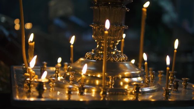 atmosphere of the Christian church, many candles burn, slow-motion shooting, smooth movement, camera slide, icons and religion, concept sacred rituals, wedding, baptism, communion, prayers to God