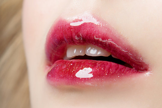 Lips with red lipstick and juicy glitter close-up. Elements of a professional make-up.
