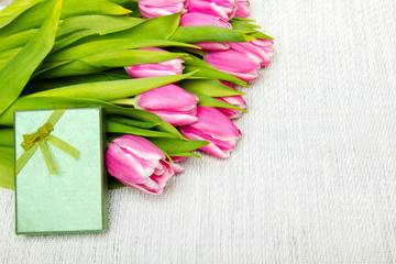 Pink tulip bouquet and small gift on light background, copy space