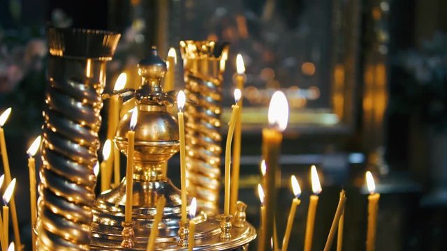 atmosphere of the Christian church, many candles burn, slow-motion shooting, smooth movement, camera slide, icons and religion, concept sacred rituals, wedding, baptism, communion, prayers to God