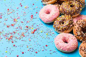 Colorful round donuts on blue background. Flat lay, top view.
