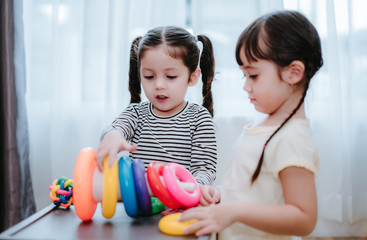 Children girls play a toy games in the room, Kids playing together with circular loop tower preschool and kindergarten education at home.