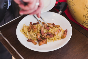 Fototapeta premium Spaghetti Carbonara made in cheese wheel topping with fried bacon on white plate.