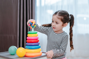 Children girl play a toy games in the room, Kid playing with circular loop tower preschool and kindergarten education at home.