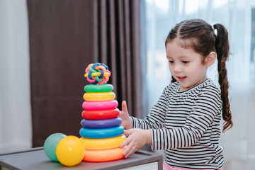 Children girl play a toy games in the room, Kid playing with circular loop tower preschool and kindergarten education at home.