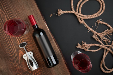  orkscrew, bottle of wine and two glasses on the wooden board on black background. Top view with...
