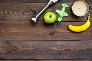 Homemade baby food. Cook puree with apple and banana with immersion blender. Dark wooden background...