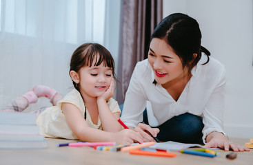 Mother and daughter study drawing with crayon paint on the paper family lifestyle, preschool and kindergarten education at home.