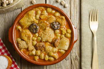 Spanish callos with chickpeas on a wooden table with golden fork