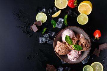 Portion of ice cream scoops with fruit on black