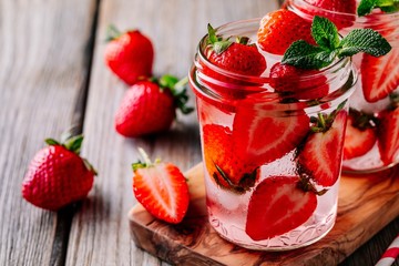 Detox water with strawberry and mint. Ice cold summer cocktail or lemonade in glass mason jar