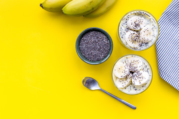 Idea for healthy breakfast. Banana pudding with chia seeds on yellow table with blue tablecloth top view copy space